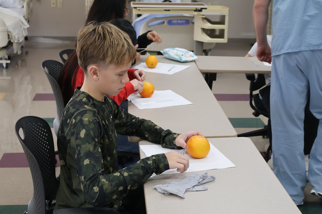 student stitching an orange