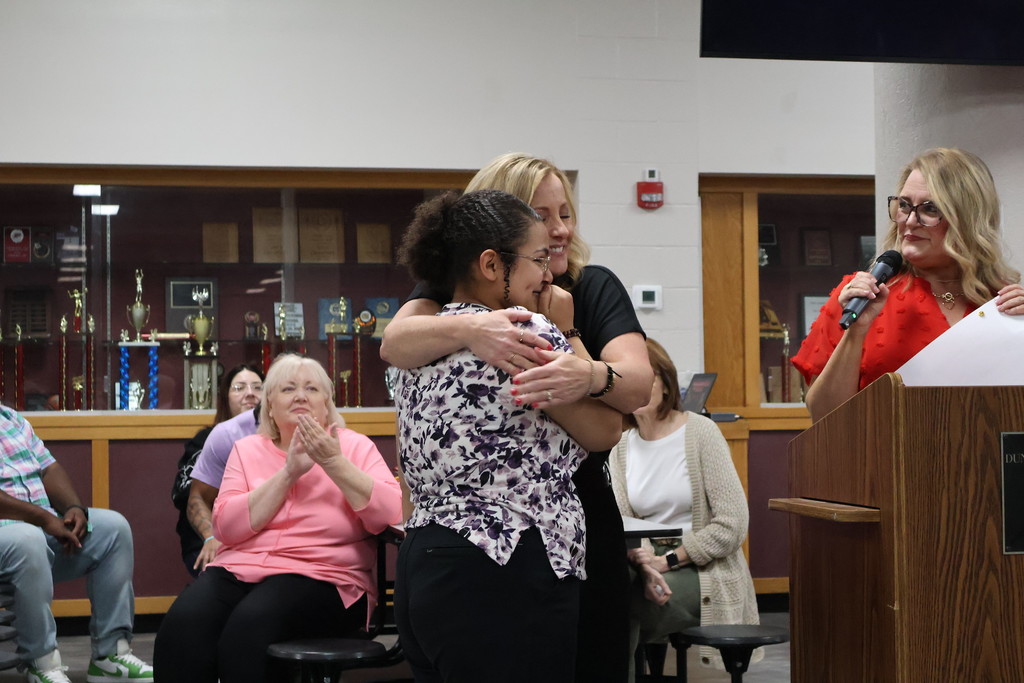 student hugging staff memeber student receiving award