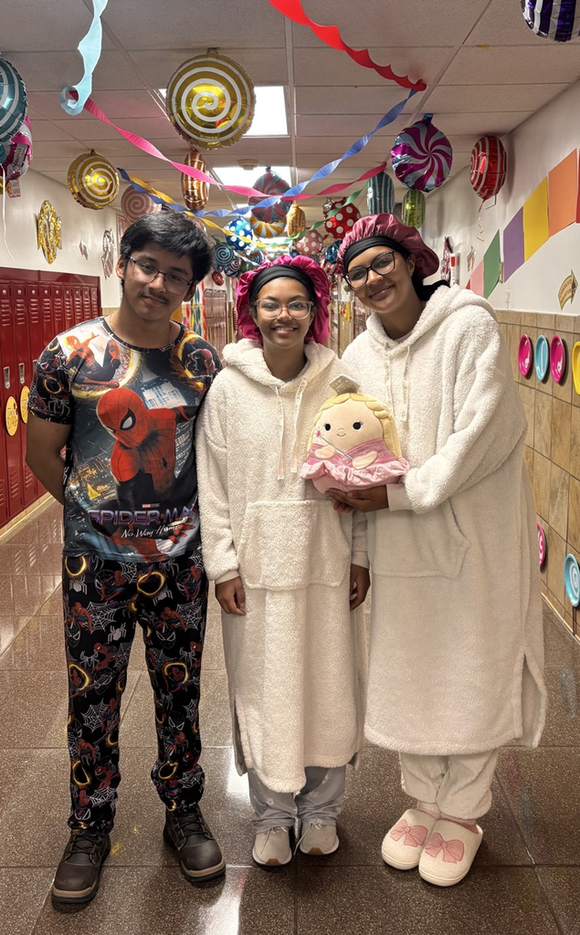 three students stand smiling in a decorated school hallway