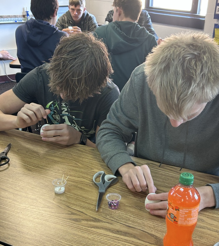 2 male students work in adding sequins to their skulls