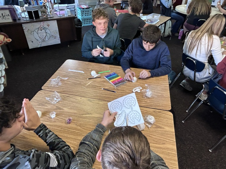 4 students work on creating hats for their skulls 