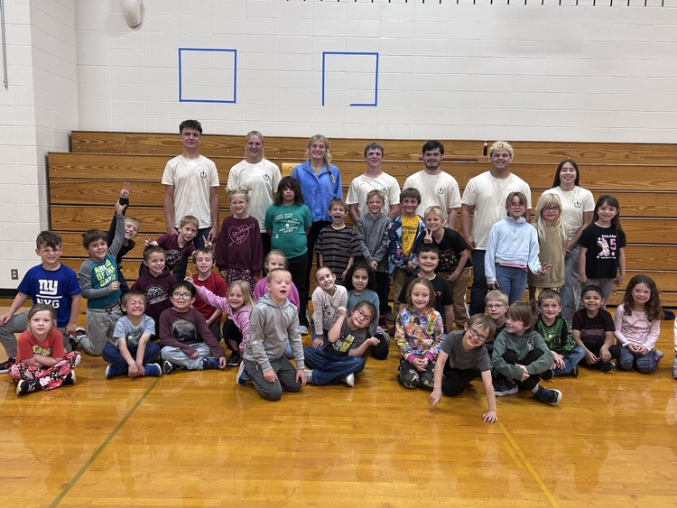 NHS members wearing yellow t-shirts pose with the kindergarten and 1st grade students
