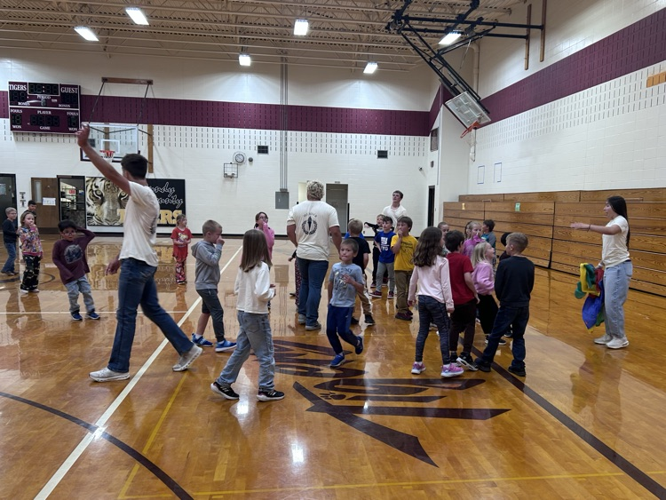 High school NHS members in yellow t-shirts lead the elementary students in their next activity in the gym