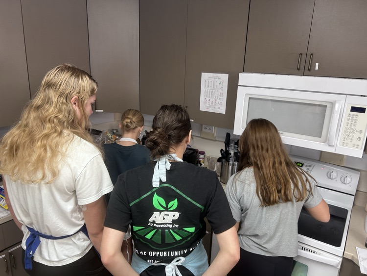 a group of four female students are grouped together getting ready to move their cooked arepas from the stove to the assembly area