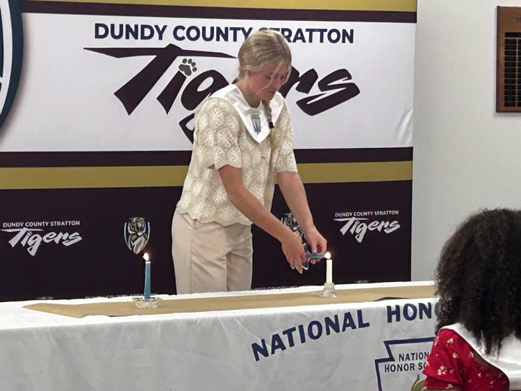 a female student holds a candle lighting it from another candle