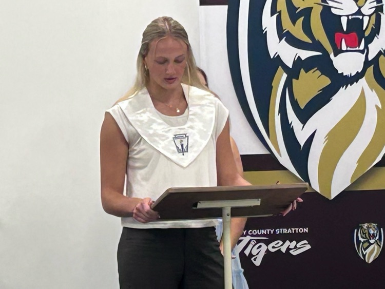a female student stands behind a podium delivering a speech