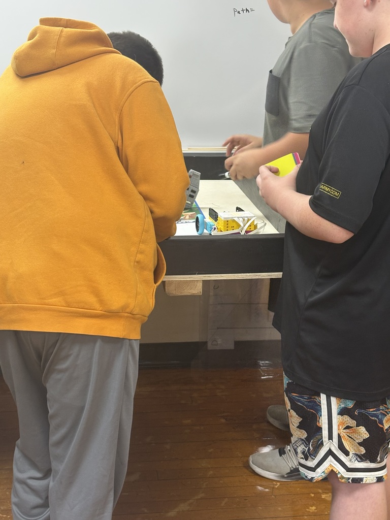 Students measuring to make their code stop the robot at the right spot. 