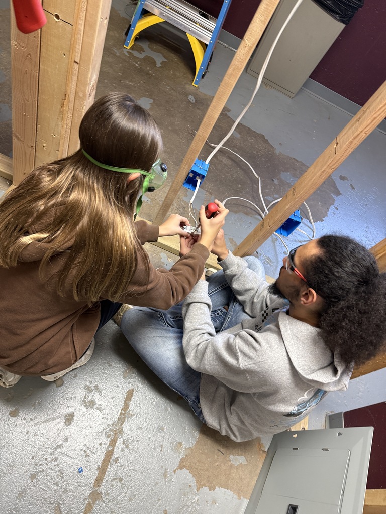 Brandon is helping a student connect wires to a duplex receptacle (outlet)