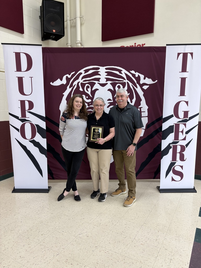 Three people stand behind a banner reading "DUPO" and "TIGERS." The middle person holds a trophy.