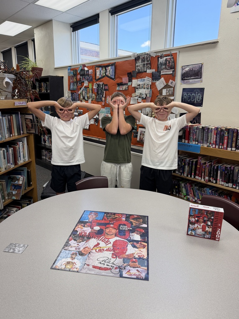 Students posing in front of a puzzle in the library