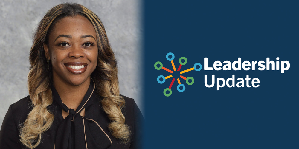 Portrait of a smiling woman with long, wavy hair on a gray background. Next to her is a blue panel with the words "Leadership Update" and a colorful graphic.