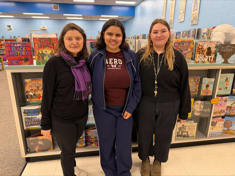 Three teachers posing in front of book display