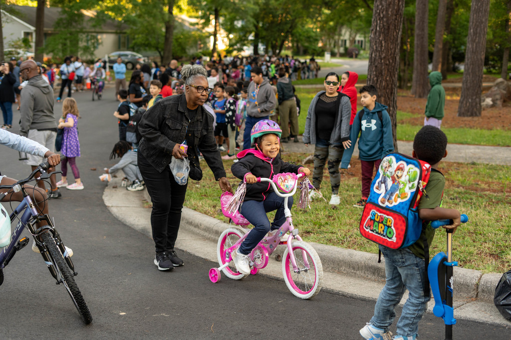 Child being pushed on her bike by a teacher