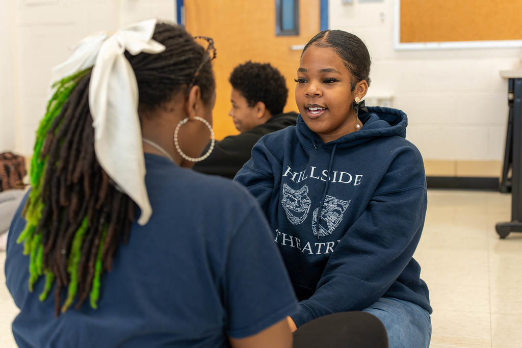 Two students talking face to face on a classroom floor