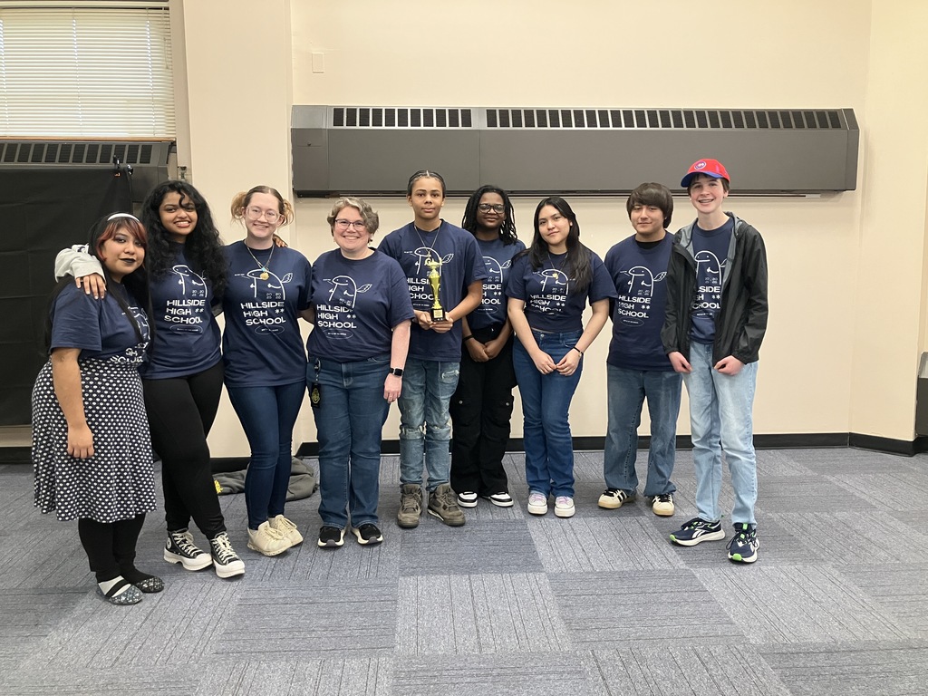 The Hillside Battle of the Books team, 8 students and their school librarian, standing in blue team shirts holding a trophy