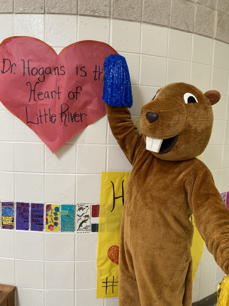 Bailey Beaver Pointing to Dr. Hogans it the Heart of Little River Sign. 