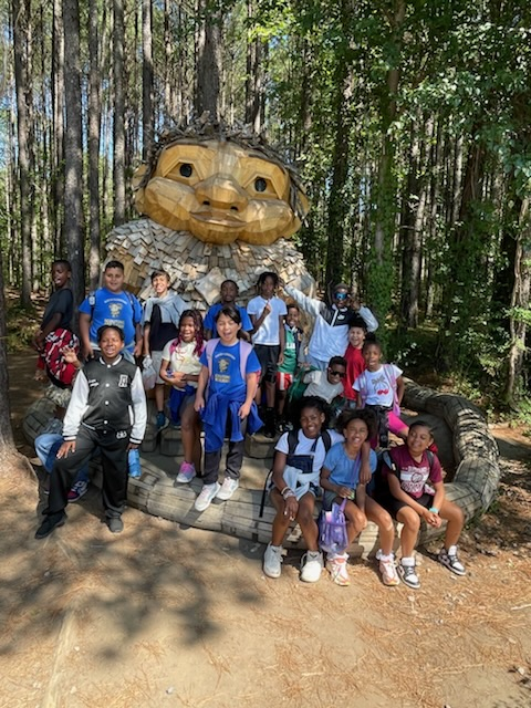 students and teachers posing in front of a big troll.