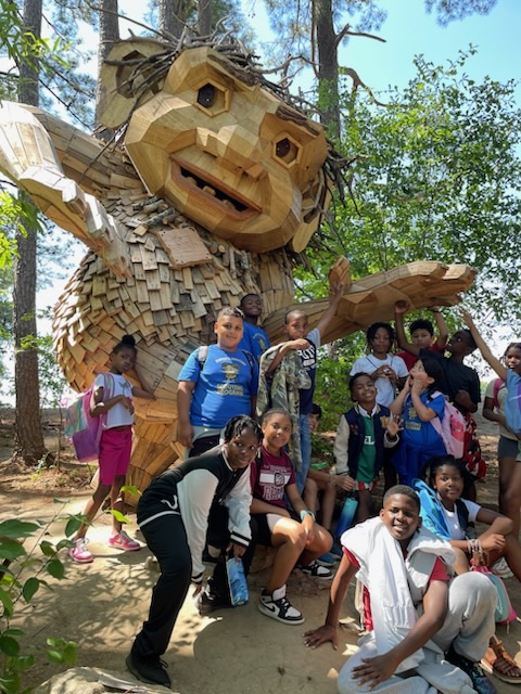 students and teachers posing in front of a big troll.