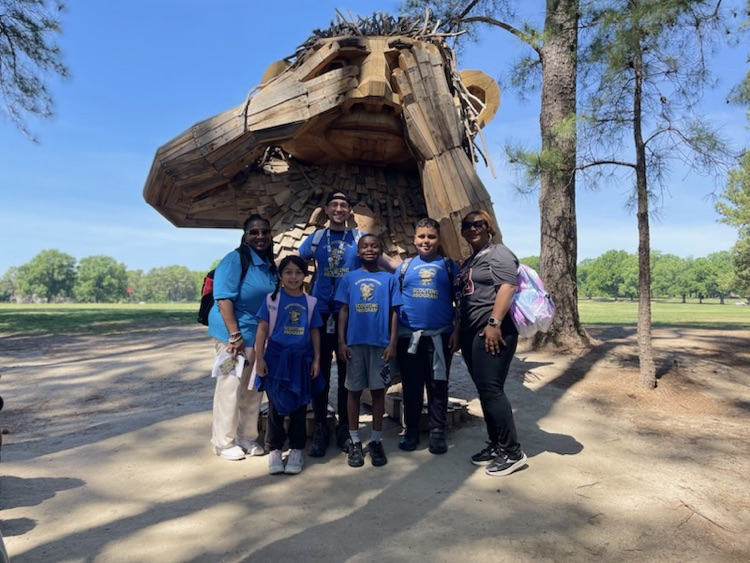 students and teachers posing in front of a big troll.