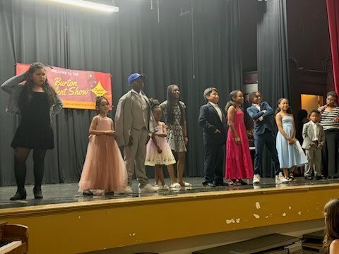 Students standing on stage displaying various fashion clothing