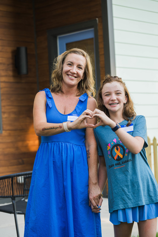 woman and child standing next to each other and holding hands to make a heart