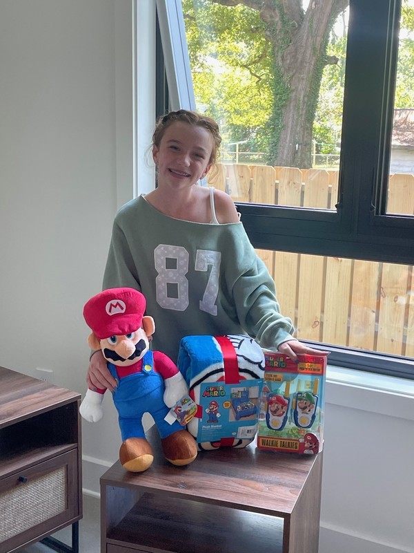 girl standing next to Mario plush and blanket