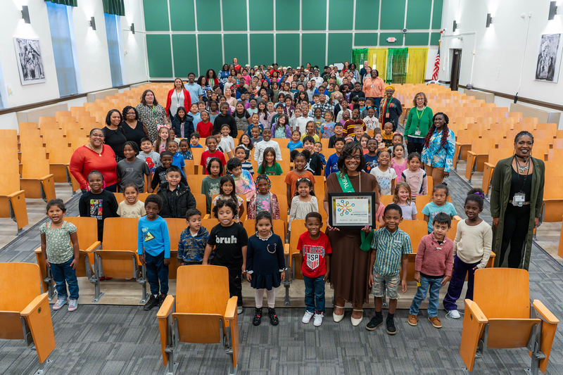 Dr. Alford standing with student body while holding her Principal of the Year certificate