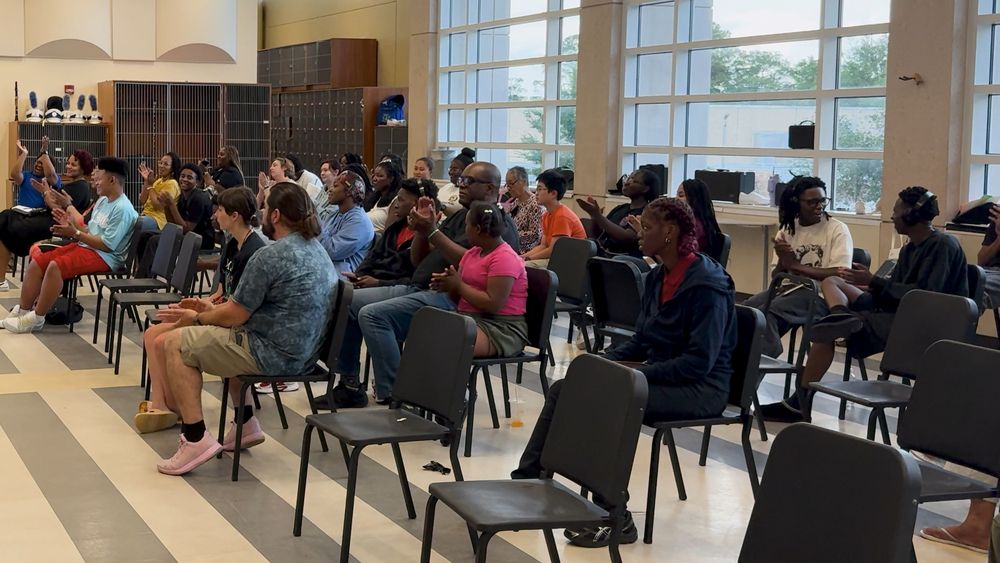 A group of band students and parents applaud at a band program meeting
