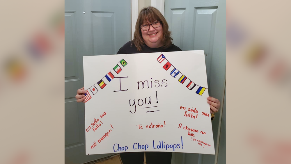 Lady holding sign that says "I miss you!" 