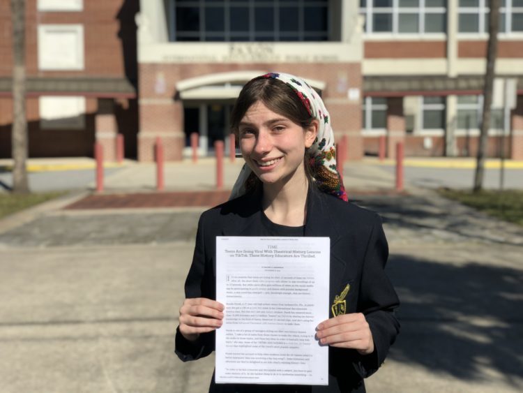 Student smiling and holding letter