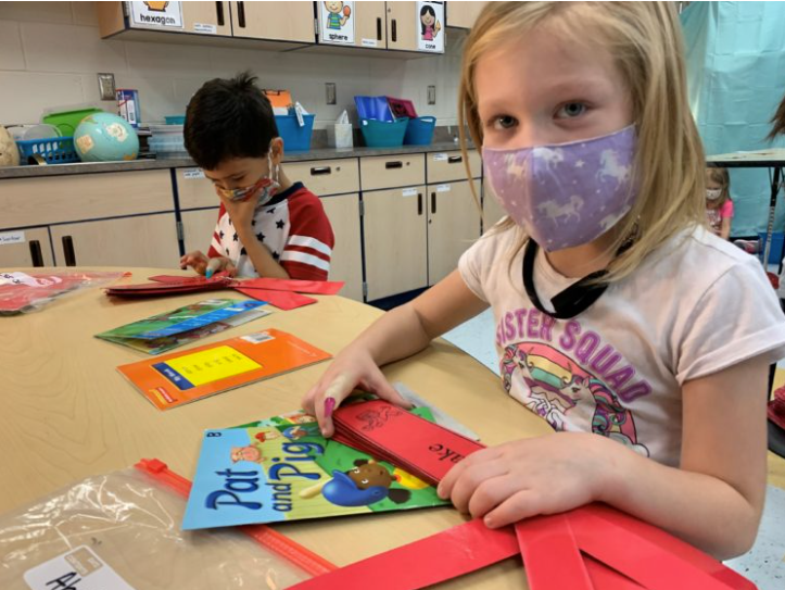Image of 2 students in masks with books in front of them