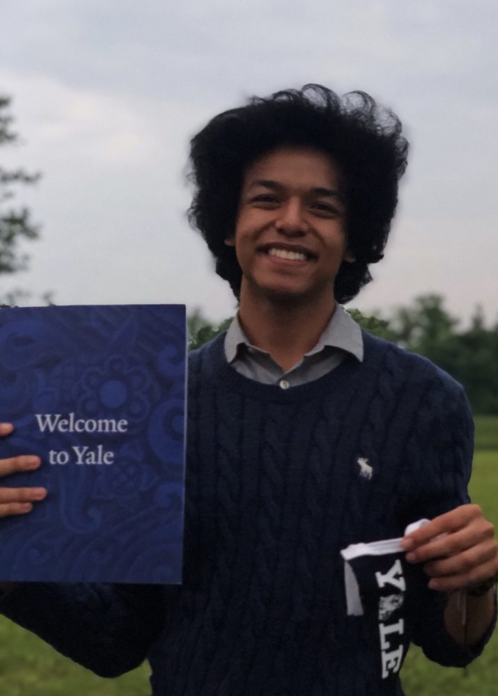 Student holding welcome pamphlet from Yale University.
