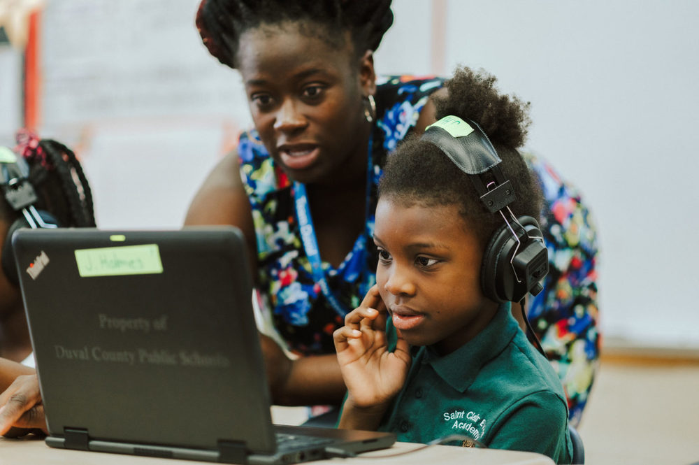Teacher looking with student at laptop