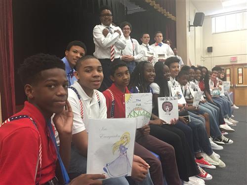 Kids sitting on a stage showing their self-written/illustrated books