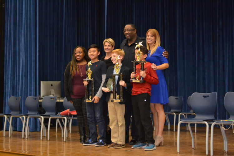 Spelling Bee winners on stage with trophies and teachers