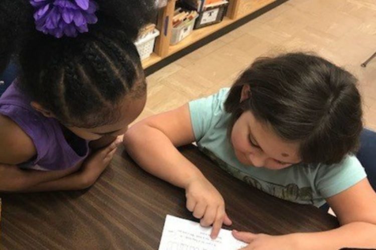 2 students in a classroom reading together