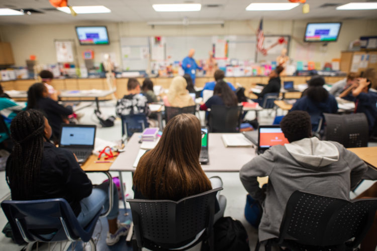 Group of people in a class room with laptops open.