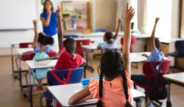 students raising hands in a classroom
