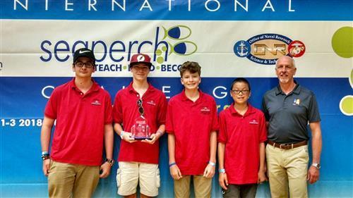 4 students and 1 teacher standing with their trophy