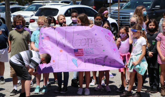 kids holding a "welcome home" sign