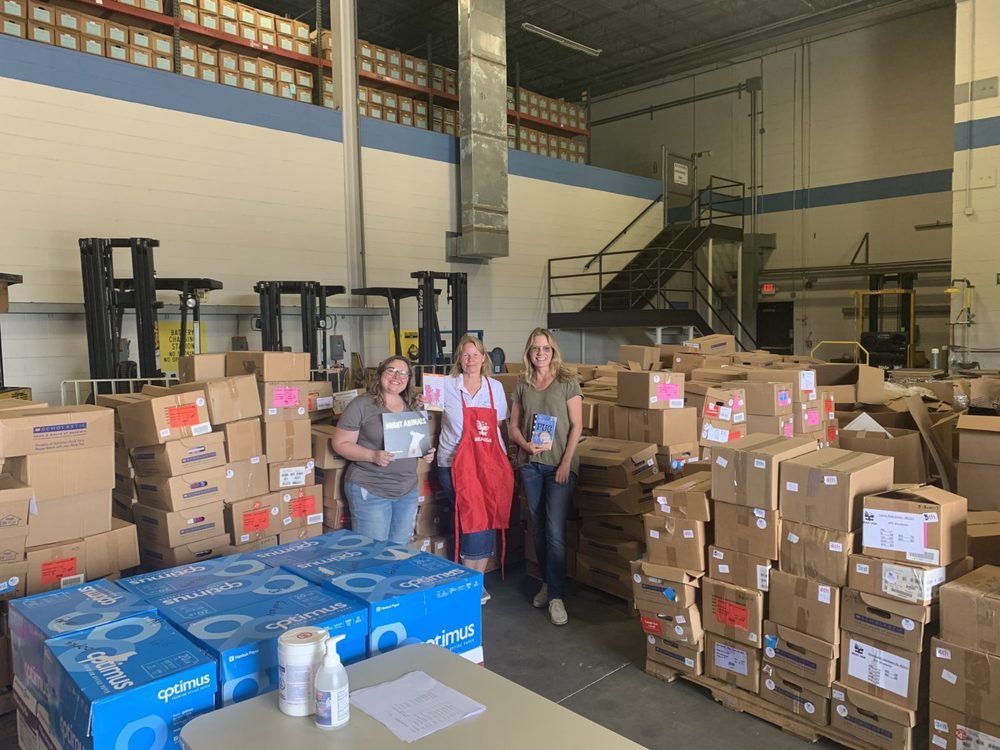 People in warehouse holding signs, standing next to boxes