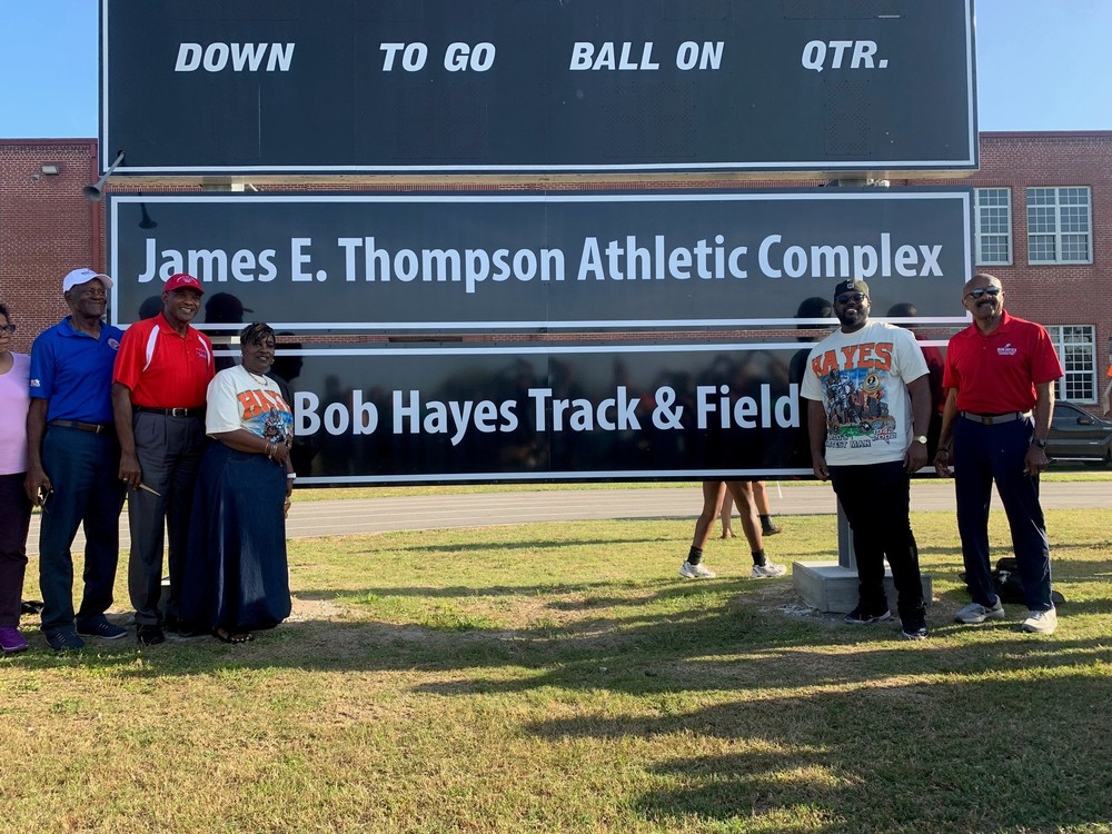 Individuals are gathered around  the new  "Bob Hayes Track & Field" marquee