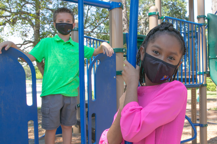 Students playing on playground equipment with Covid-19 Face masks on. 