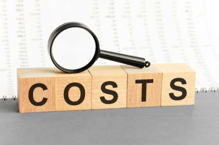An image of a magnifying glass on wooden blocks that spell out the word "costs"