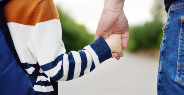 Upclose of parent and child holding hands. 