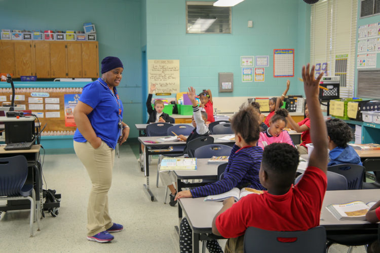 students raising hands in a classroom