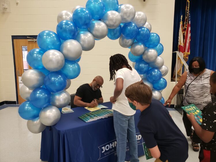 John E. Ford signing autographs to students