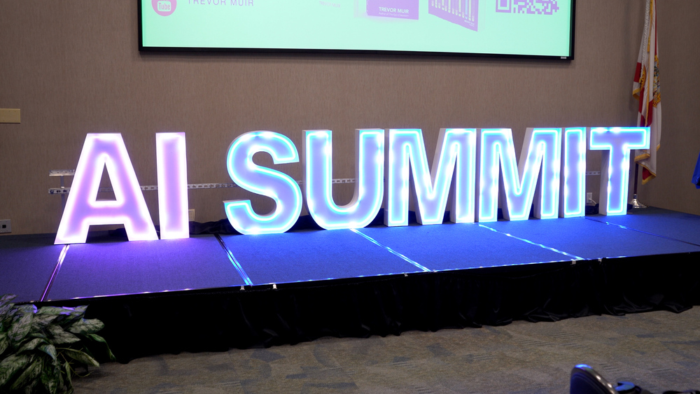 A glowing LED sign that reads "AI Summit" on stage at the DCPS AI Summit.