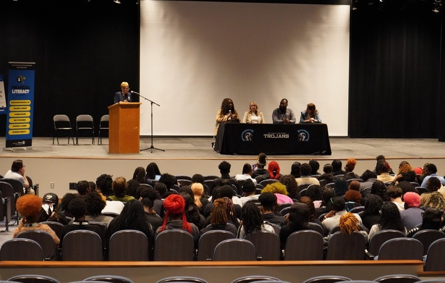 Students seated in an auditorium before a panel of guest speakers
