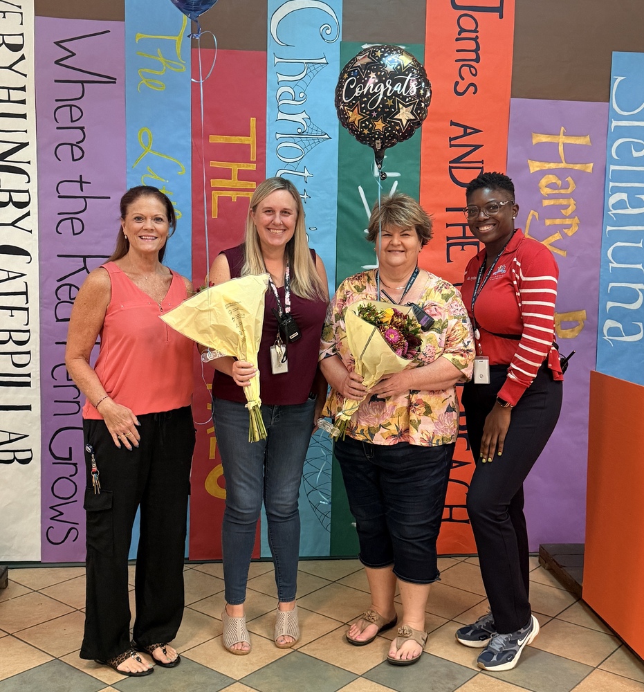 4 women standing with flowers and balloons
